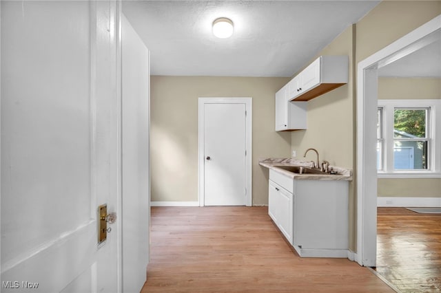 kitchen featuring white cabinets, light hardwood / wood-style flooring, and sink