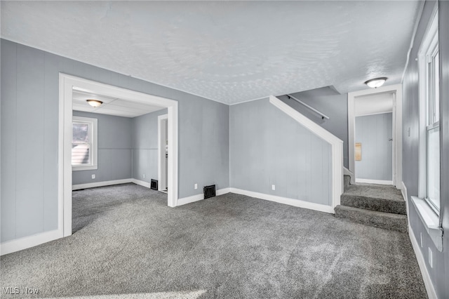 unfurnished living room featuring dark carpet and a textured ceiling