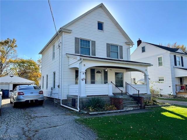 view of property featuring a garage, covered porch, and a front yard