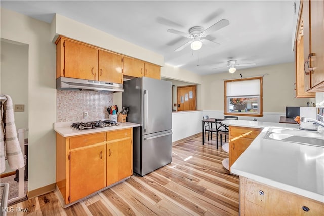 kitchen with tasteful backsplash, appliances with stainless steel finishes, sink, and light hardwood / wood-style floors