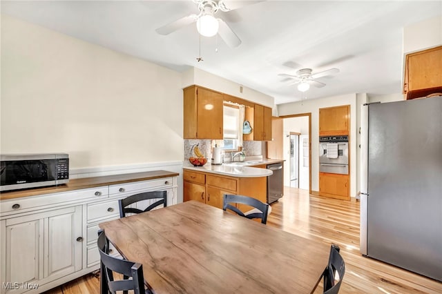 kitchen with kitchen peninsula, appliances with stainless steel finishes, backsplash, and light hardwood / wood-style flooring