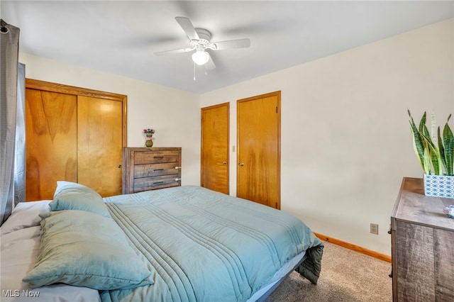 carpeted bedroom with ceiling fan and two closets