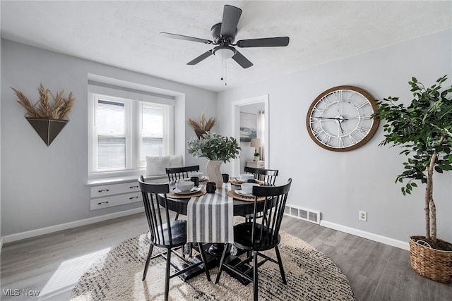 dining space with ceiling fan, wood-type flooring, and a textured ceiling