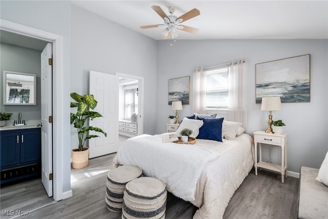 bedroom featuring ceiling fan, sink, ensuite bathroom, hardwood / wood-style floors, and vaulted ceiling