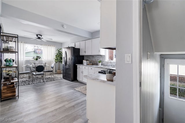 kitchen with white cabinets, light hardwood / wood-style flooring, black refrigerator with ice dispenser, and ceiling fan