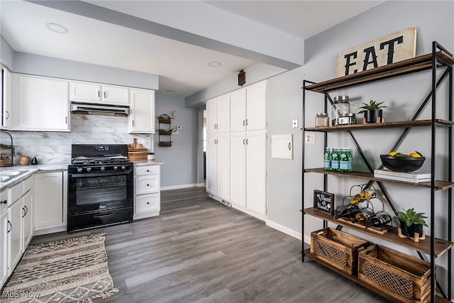 kitchen with black gas range oven, dark hardwood / wood-style floors, white cabinetry, and tasteful backsplash