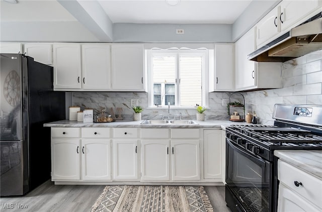 kitchen featuring backsplash, black appliances, white cabinets, sink, and light wood-type flooring