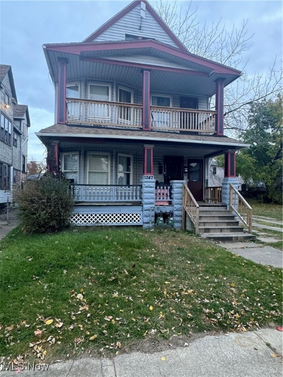 view of front of property with a front yard, covered porch, and a balcony