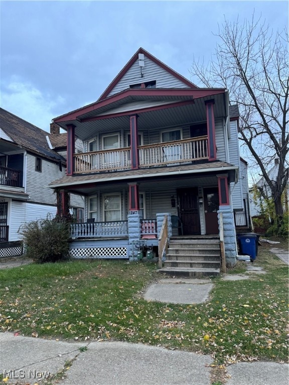 view of front of house with covered porch, a front lawn, and a balcony