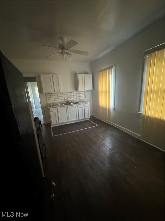 unfurnished living room featuring ceiling fan, sink, and dark hardwood / wood-style floors