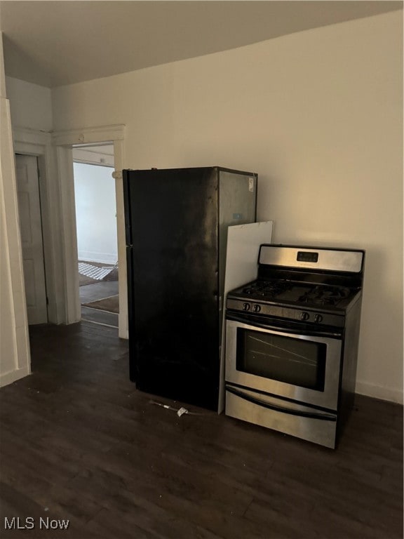 kitchen featuring stainless steel range with gas stovetop, dark hardwood / wood-style floors, and black fridge