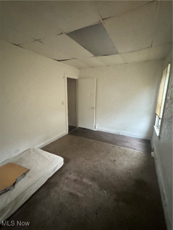 carpeted empty room featuring a paneled ceiling