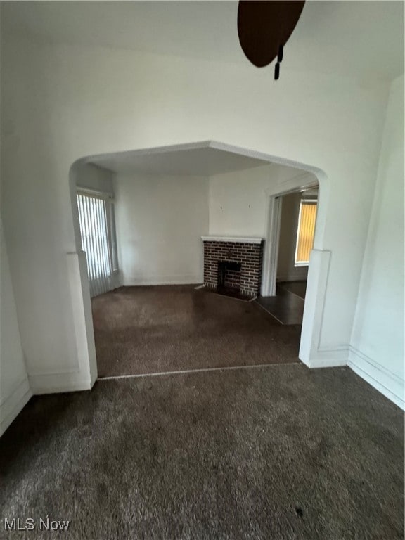 unfurnished living room with a fireplace and dark colored carpet