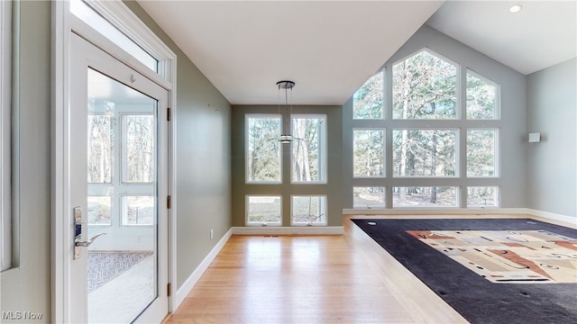 doorway to outside with light hardwood / wood-style floors, plenty of natural light, and lofted ceiling