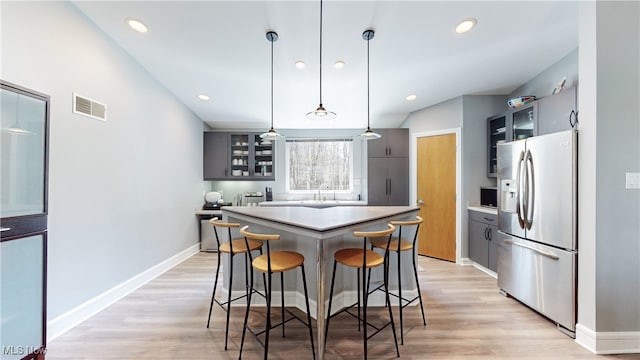 kitchen with sink, decorative light fixtures, light hardwood / wood-style flooring, a center island, and stainless steel fridge