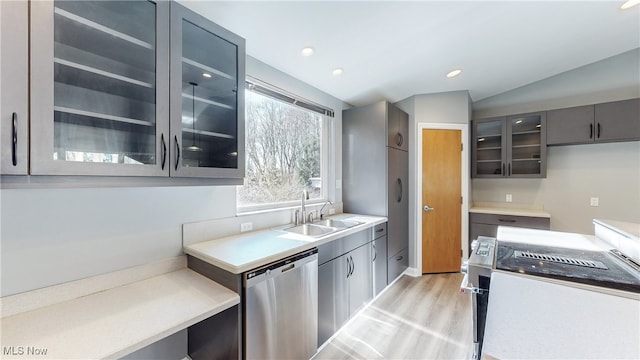 kitchen featuring dishwasher, light hardwood / wood-style floors, sink, and vaulted ceiling