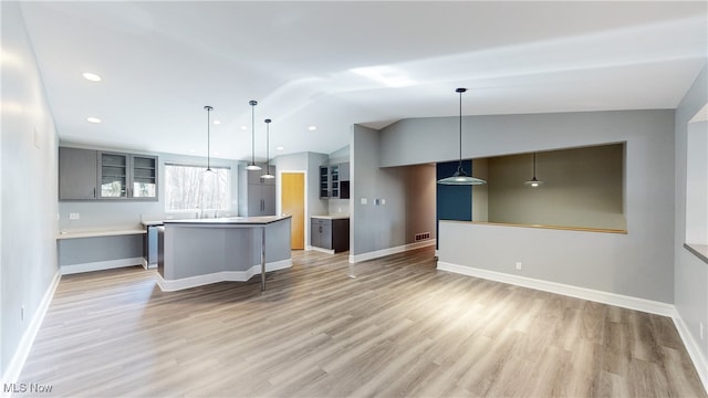 kitchen featuring hanging light fixtures, light hardwood / wood-style floors, vaulted ceiling, and gray cabinets