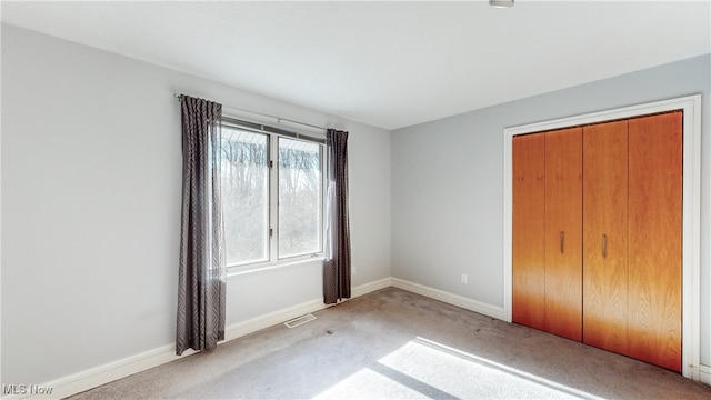 unfurnished bedroom featuring light colored carpet and a closet