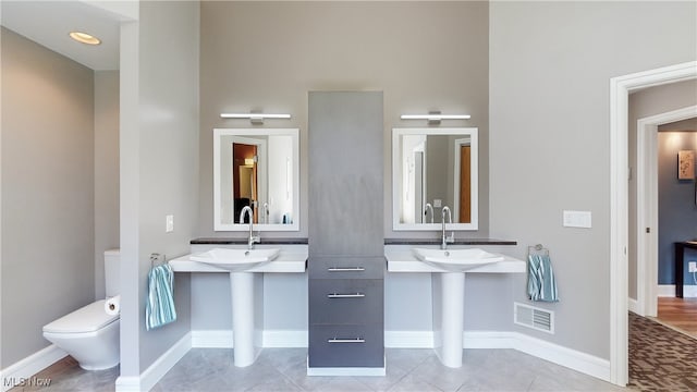 bathroom with dual sinks and toilet