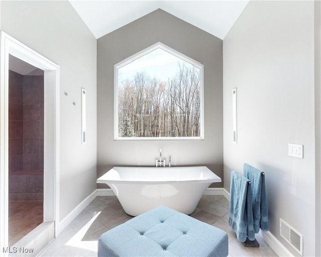 bathroom with a bathing tub, lofted ceiling, and tile patterned floors