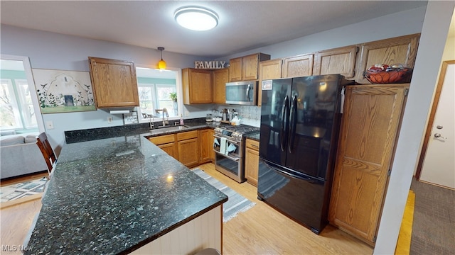 kitchen featuring decorative backsplash, appliances with stainless steel finishes, dark stone counters, sink, and pendant lighting