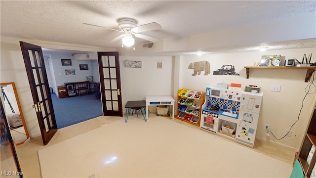 game room with ceiling fan, a textured ceiling, light carpet, and french doors