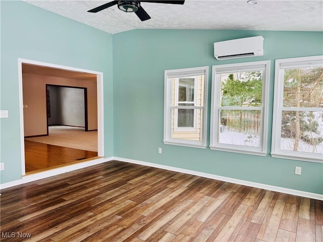 empty room featuring a wall unit AC, a textured ceiling, and vaulted ceiling