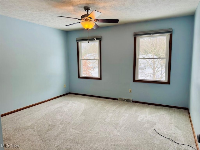 carpeted spare room with a wealth of natural light, ceiling fan, and a textured ceiling