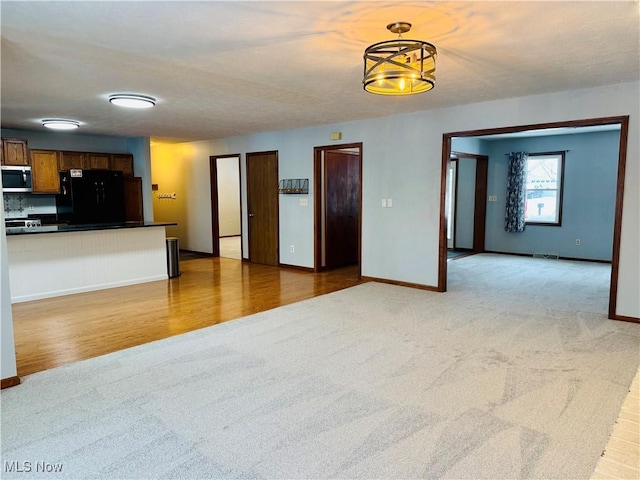 unfurnished living room featuring light colored carpet and a chandelier