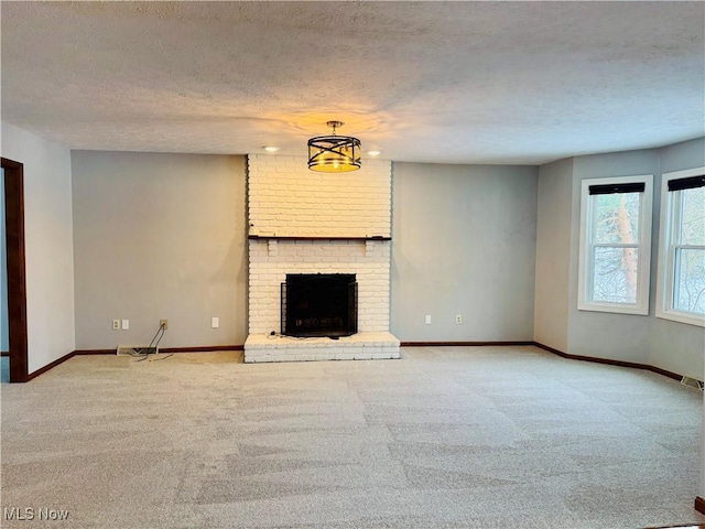 unfurnished living room with light colored carpet, a textured ceiling, and a brick fireplace