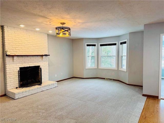 unfurnished living room featuring a textured ceiling and a brick fireplace