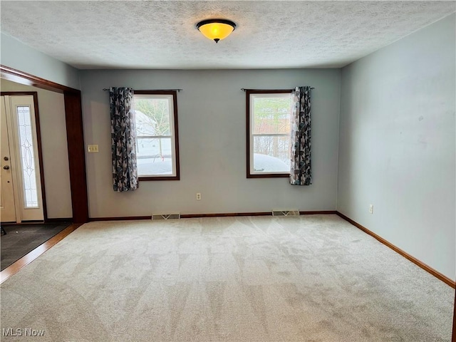 spare room featuring a textured ceiling and light carpet