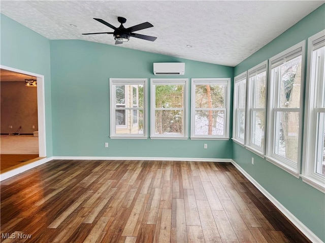 unfurnished sunroom with an AC wall unit, ceiling fan, and lofted ceiling