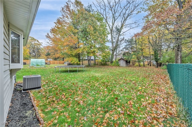 view of yard with central air condition unit, a storage shed, and a trampoline