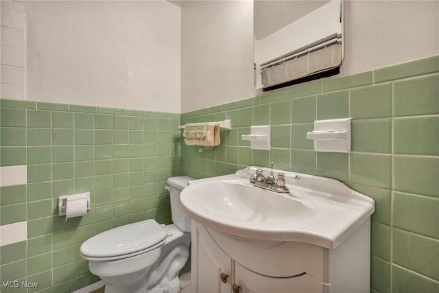 bathroom featuring vanity, toilet, and tile walls