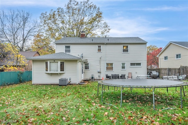 rear view of house with central AC unit and a lawn