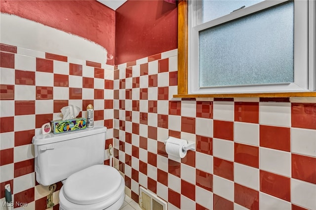 bathroom with tile walls, a healthy amount of sunlight, and toilet