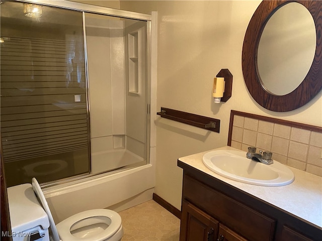 full bathroom with toilet, tile patterned flooring, combined bath / shower with glass door, vanity, and backsplash