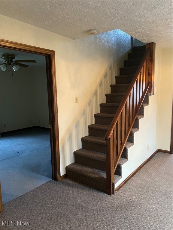 stairway with a textured ceiling, ceiling fan, and carpet floors