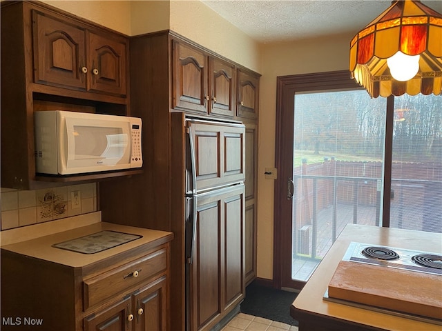 kitchen with stainless steel electric stovetop, paneled built in fridge, a wealth of natural light, and tasteful backsplash