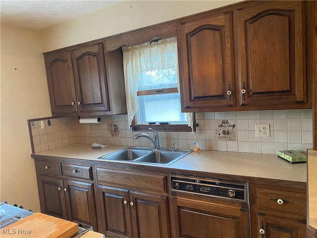 kitchen featuring dark brown cabinetry, sink, tasteful backsplash, a textured ceiling, and dishwasher