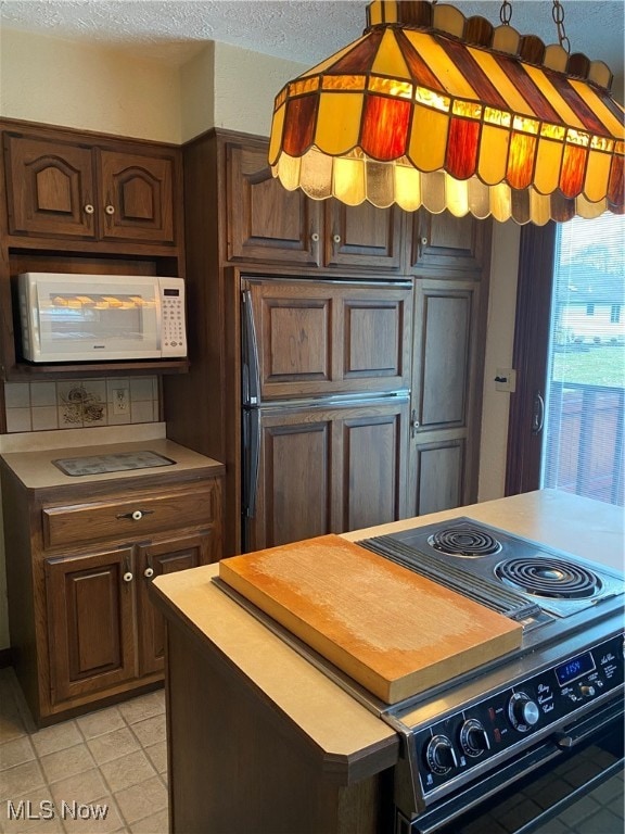 kitchen with dark brown cabinets, a textured ceiling, black range, and paneled fridge