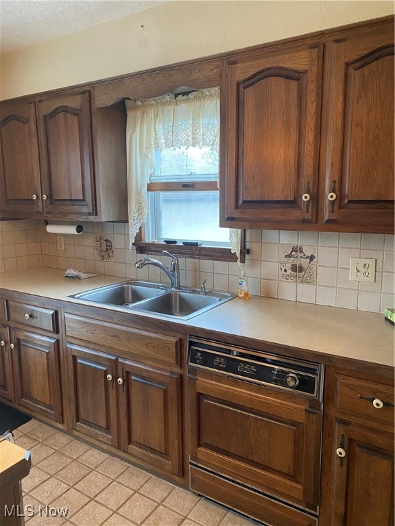 kitchen featuring light tile patterned flooring, sink, paneled dishwasher, and tasteful backsplash