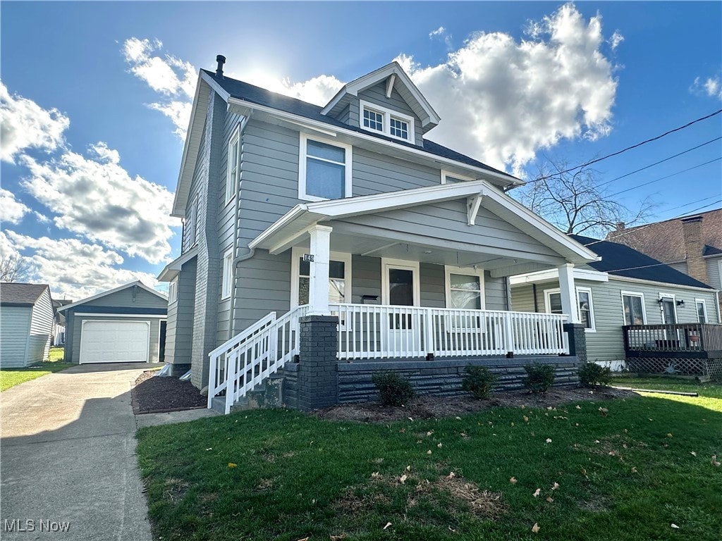 view of front of home with a garage, a front yard, covered porch, and an outdoor structure