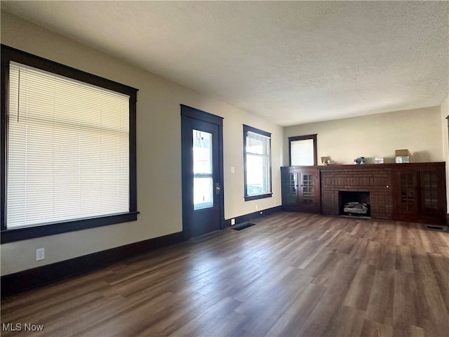 unfurnished living room with a textured ceiling, a fireplace, and dark hardwood / wood-style floors