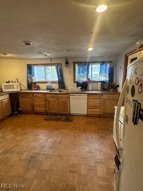 kitchen with white appliances, sink, and light parquet floors