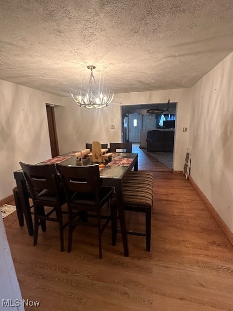 dining room with an inviting chandelier, wood-type flooring, and a textured ceiling