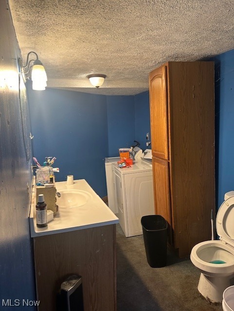 bathroom featuring washing machine and dryer, a textured ceiling, toilet, and vanity