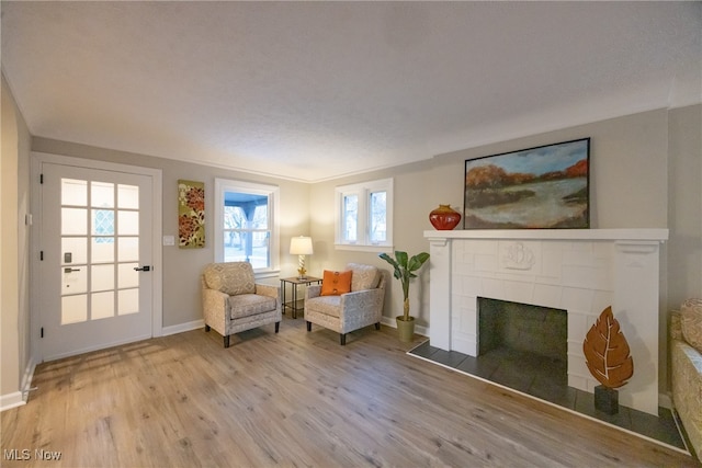 sitting room featuring light hardwood / wood-style flooring, a tile fireplace, and plenty of natural light