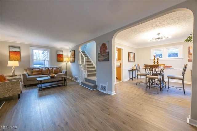 living room featuring wood-type flooring, a textured ceiling, and crown molding